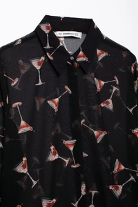 Détail de l'étiquette du col sur une chemise en mousseline noire à imprimé cocktail rouge
