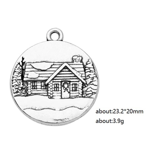 Detailed relief of a snowy cabin and trees on a silver alloy circular charm pendant