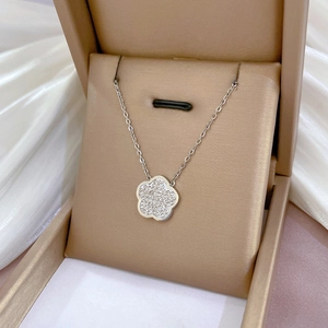 Detailed view of a silver flower necklace with crystals in a gold jewelry box