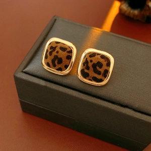 Detail of square leopard print earrings with gold metal frame on a velvet jewelry box