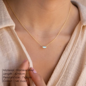 Detail of 14K gold stainless steel necklace featuring a small blue gemstone pendant
