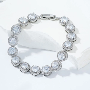 Detail of silver-tone halo bracelet featuring round zircon stones on white marble background
