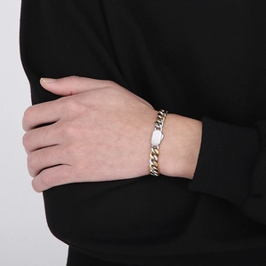 Close-up of a two-tone silver and gold Cuban link chain bracelet on a model wrist
