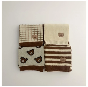 Detail of children's knit scarves in plaid, solid, bear print, and striped patterns