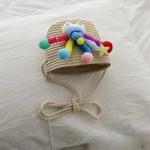 Close-up of kids straw crossbody bag featuring colorful plush balls and golden sequin star