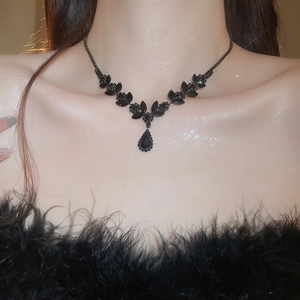 Macro view of water drop black gemstone pendant and marquise petals on the collarbone