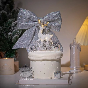 Detail of silver glitter Christmas bow with glowing reindeer topper and cake decorations