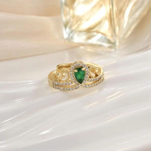 Macro shot of crown ring with teardrop emerald and pavé crystals on golden band