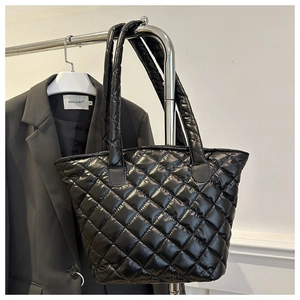 Détail d'un sac cabas matelassé noir brillant suspendu sur un support métallique
