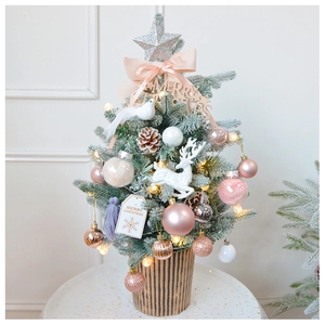 Close-up of mini desktop Christmas tree with pink and gold ornaments and LED lights