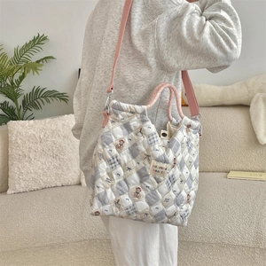 Close-up of quilted tote bag featuring cute cartoon bear prints and woven handles