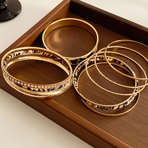 Detail of leopard print leather and gold bangles with white rhinestones on dark wood