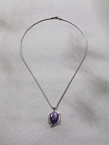 Detail of silver twisted chain with oval purple gemstone pendant and small crystals