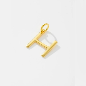 Detailed macro view of gold H-letter pendant with a polished mirror finish surface