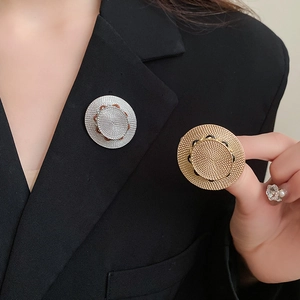 Minimalistische Strohhut-Brosche in Gold und Silber auf einem schwarzen Revers