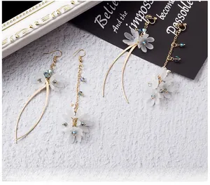 Gros plan de boucles d'oreilles fleurs blanches avec pétales mats et détails dorés