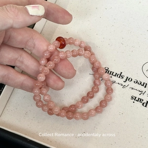 Detail of pink strawberry quartz double-layer beaded bracelet with agate charm