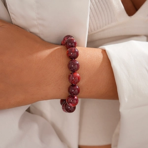 Detail of dark red marble-patterned acrylic beaded bracelet on model wrist