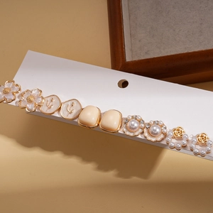 Detail of a 10-piece earring set featuring cream resin flowers and pearls on a white card