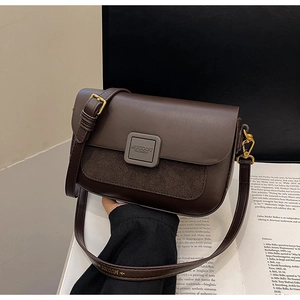 Close-up of retro brown leather shoulder bag with gold buckle and textured patchwork detail
