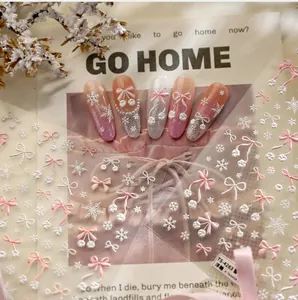 Macro detail of embossed nail art stickers with 3D pink bows and white snowflakes