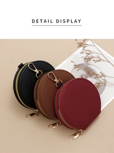 Three circular lychee pattern leather coin purses in black, brown, and red with gold zippers