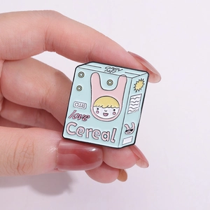 Vue d'un pin's émaillé vert menthe en forme de boîte de céréales avec un dessin de garçon