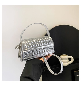 Detail of silver metallic handbag showing quilted flap and faux crocodile texture