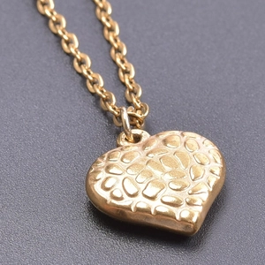 Macro shot of gold stainless steel heart pendant with unique pebbled texture finish