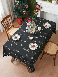 Detail of black linen tablecloth with white reindeer embroidery and festive tassel edges
