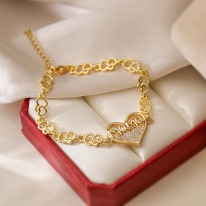 Macro shot of 18K gold plated MOMO heart pendant bracelet on white silk background