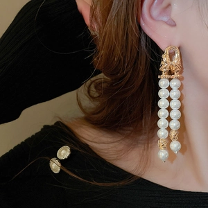 Detailed close-up of double-layered faux pearl tassel earrings with golden bow design