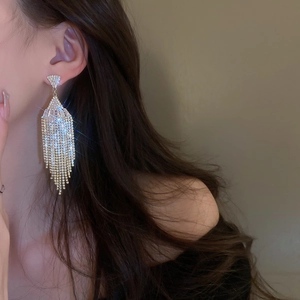 Close-up of elegant gold tassel earrings with shimmering crystals on model's ear