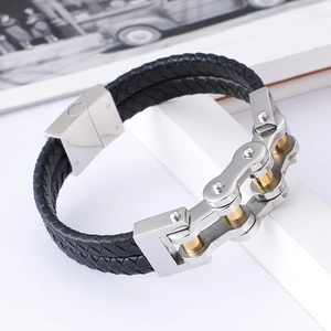 Detail eines schwarzen Lederarmbands mit silberner und goldener Edelstahlkette