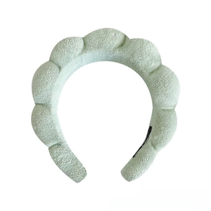 Close-up of light green padded sponge headband with soft towel fabric texture