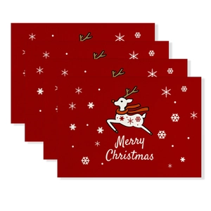 Close-up of four red Christmas placemats with white reindeer and snowflake patterns