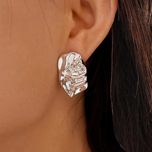 Detail view of silver textured earrings with irregular crumpled design on female model
