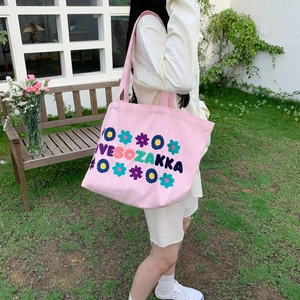Detail of embroidered floral canvas tote bag in pink featuring French chic style