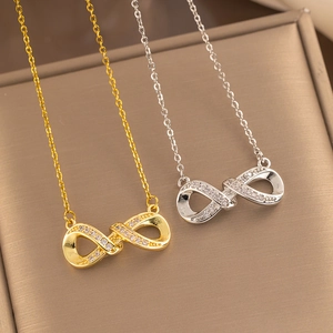 Elegant gold and silver infinity pendant necklaces with crystals on a metal gift box