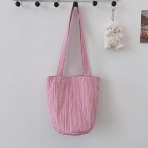 Detail van roze geplooide draagtas hangend aan de muur met een schattige schaap-accessoire