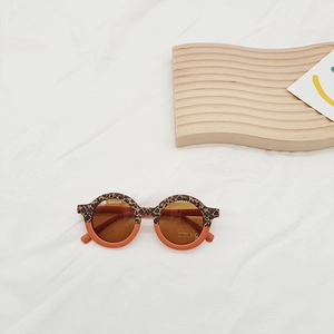 Detail of round leopard print kids sunglasses on white fabric with UV400 CE label