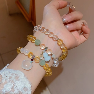 Detail of beaded bracelet set with yellow citrine and blue gourd charm on model wrist