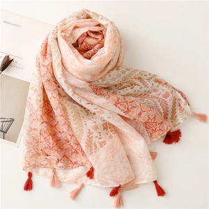 Detail of bohemian orange shawl with ethnic floral patterns and tassel trim decorations