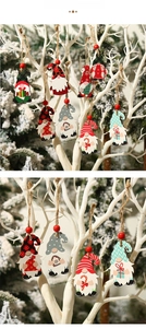 Detail view of colorful wooden Christmas gnomes hanging on tree branches with rustic twine