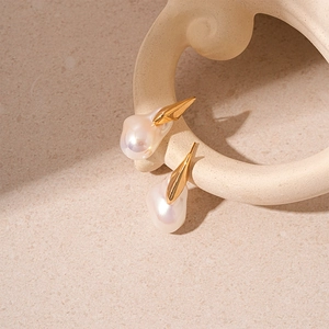 Gros plan de boucles d'oreilles perles baroques élégantes avec design en métal doré