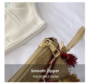 Detail of woven straw clutch showing smooth golden zipper and brown fringe tassels