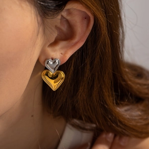 Makroaufnahme von zweifarbigen Herz-Ohrsteckern mit Silber- und Gold-Metall-Finish