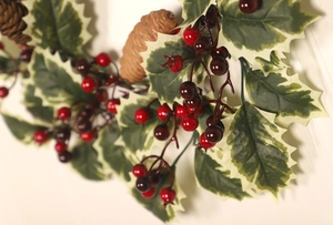 Close-up of Christmas garland with pine cones, holly leaves and red berries