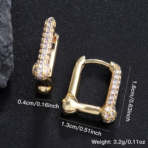 U-shaped gold geometric hoop earrings with cubic zirconia on a dark textured background
