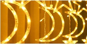 Close-up of warm yellow LED star and moon shaped hanging curtain lights for decor